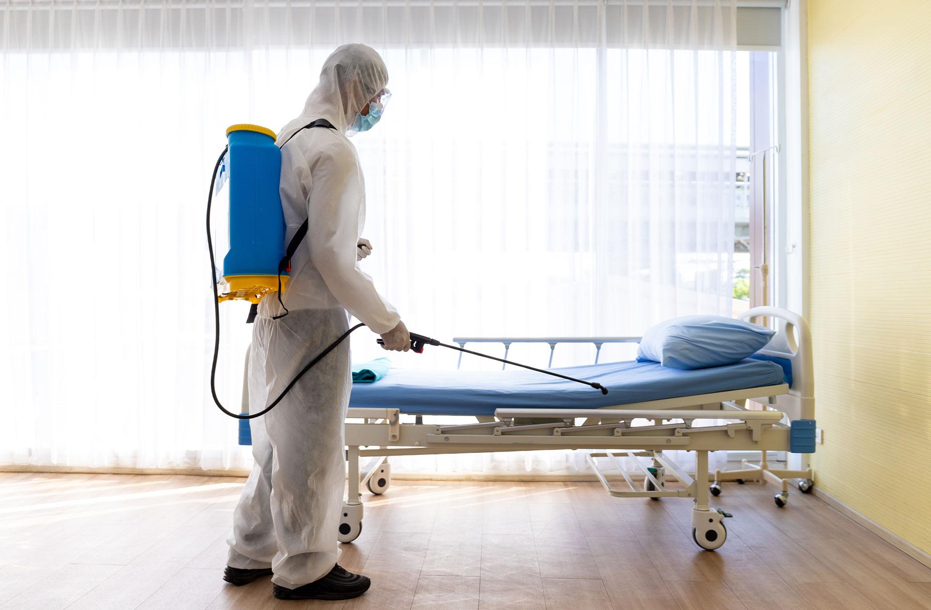 Man disinfecting hospital bed